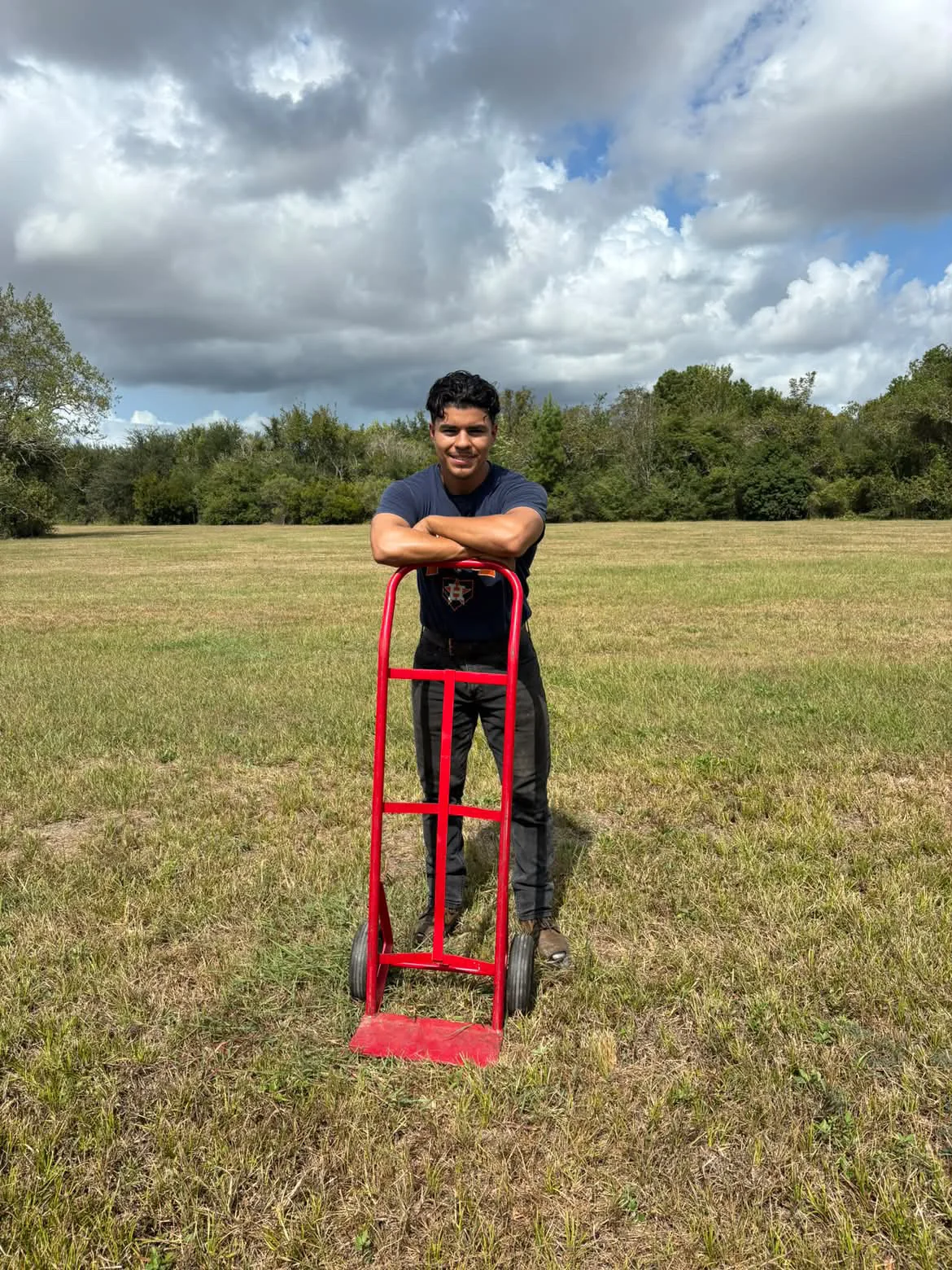 An AOA team member with a red hand truck outdoors